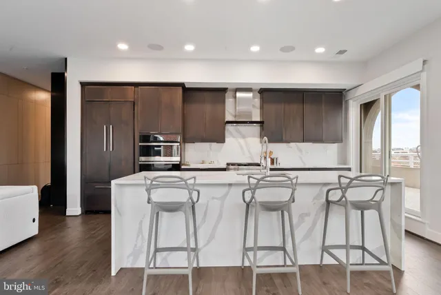 a kitchen with stainless steel appliances a refrigerator a stove a sink dishwasher with a dining table and chairs with wooden floor