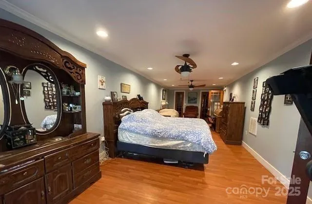 a spacious bedroom with a bed a mirror on dresser and a chandelier