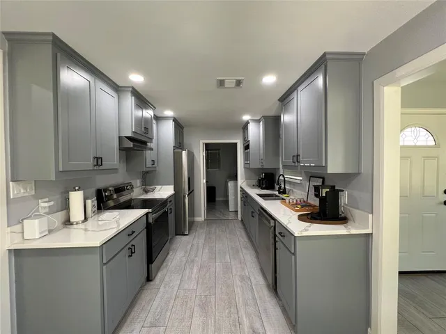 a kitchen with a sink stove top oven and refrigerator
