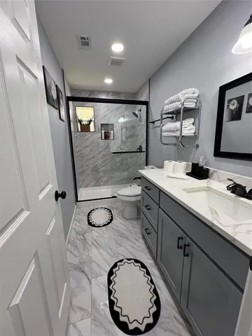 a bathroom with a granite countertop sink mirror vanity and toilet