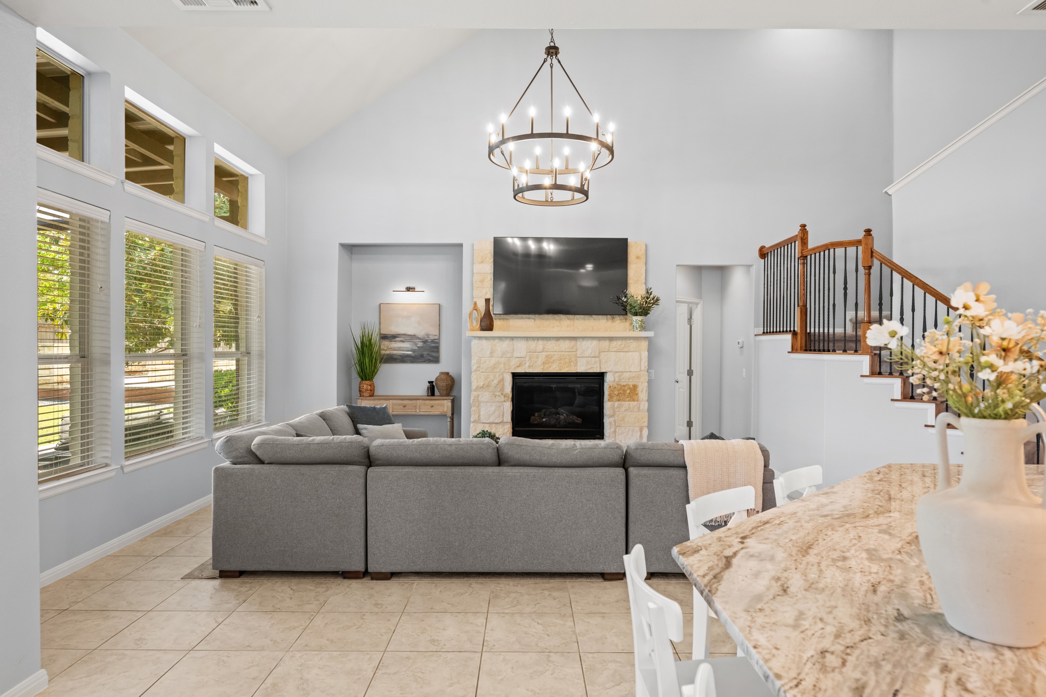 1023 Grassy Field Road Austin, TX 78737 - Photo 7 of 40 Vaulted ceiling living area featuring a stone-clad fireplace, a wrought iron chandelier, and tile flooring