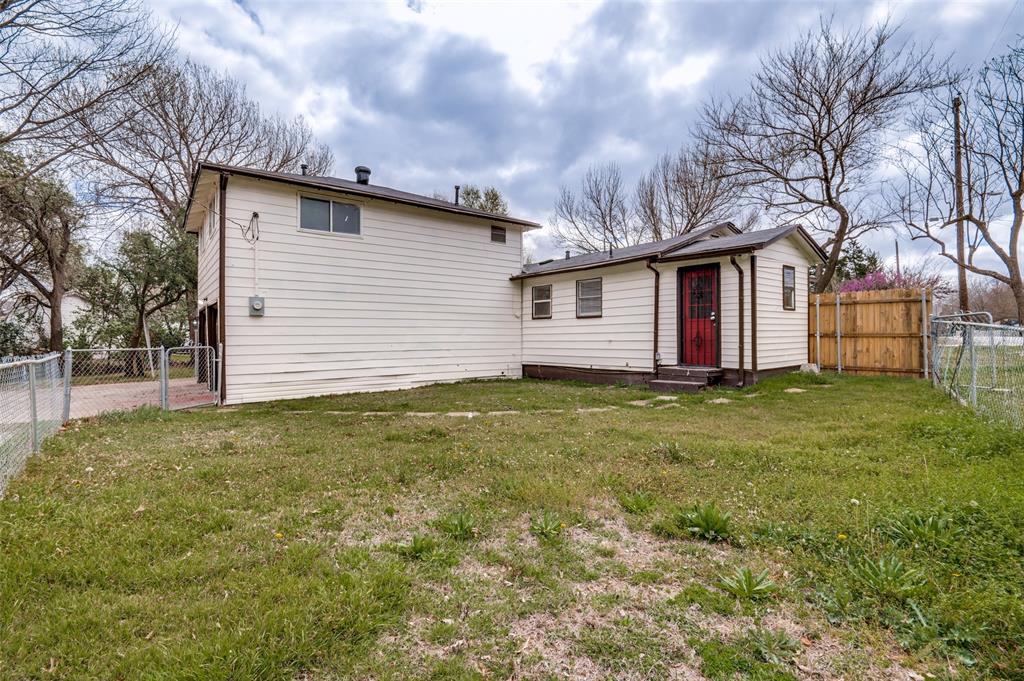 421 West 8th Street Lancaster, TX 75146 - Photo 24 of 28 Expansive grassy yard area featuring chain-link fencing, a wooden privacy fence, and a two-story structure with attached single-story section