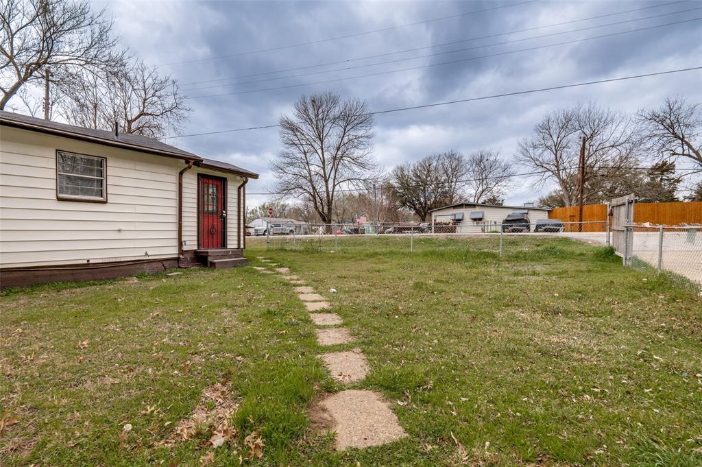 421 West 8th Street Lancaster, TX 75146 - Photo 25 of 28 Rear entry featuring a red security door, white siding, and a stepping stone path
