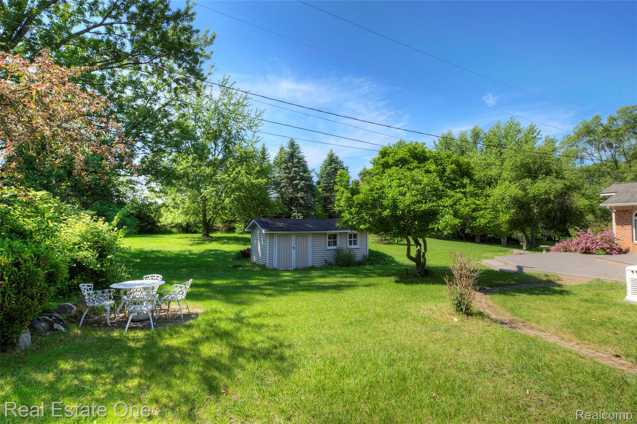 3125 West Commerce Road Milford, MI 48380 - Photo 2 of 63 Expansive lawn area featuring a detached storage shed, mature trees, and established perimeter shrubbery