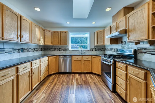 a kitchen with wooden floors wooden cabinets a sink and a stove
