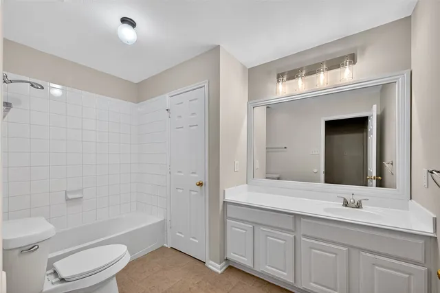 a bathroom with a toilet a sink a mirror a bathtub and vanity