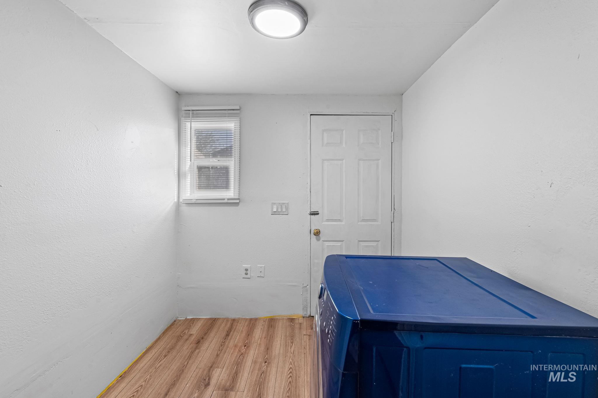 20106 Lower Pleasant Ridge Road, Unit 29 Caldwell, ID 83607 - Photo 16 of 19 Utility space featuring wood-finish flooring, a flush-mount ceiling light, and a white paneled door