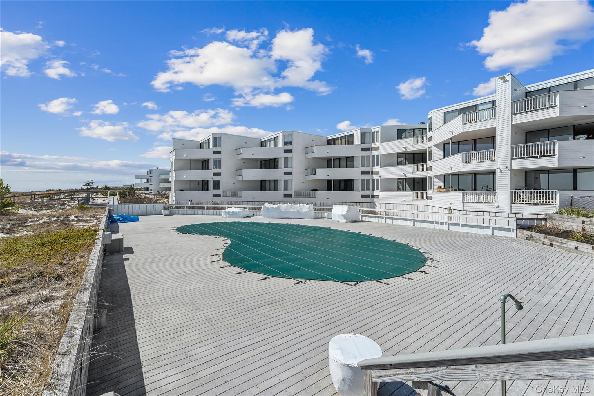 253 Dune Road, Unit 48 Westhampton Beach, NY 11978 - Photo 25 of 28 a view of a swimming pool with a lounge chairs