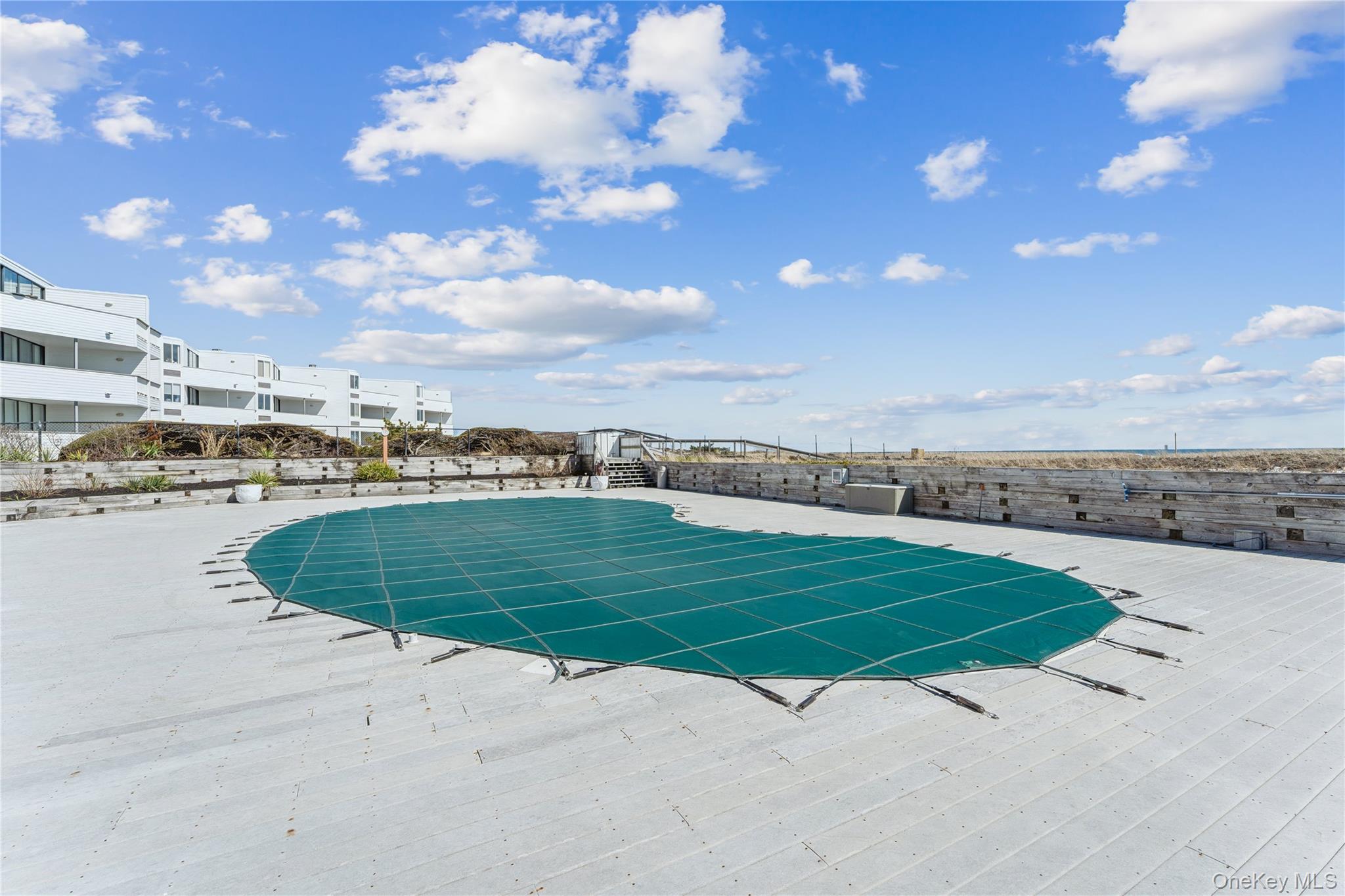 253 Dune Road, Unit 48 Westhampton Beach, NY 11978 - Photo 26 of 28 a view of a swimming pool with a yard