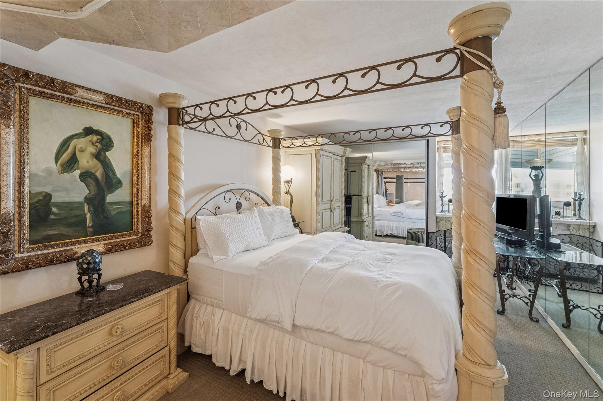 253 Dune Road, Unit 48 Westhampton Beach, NY 11978 - Photo 9 of 28 a bedroom with a large bed and a mirror on dresser