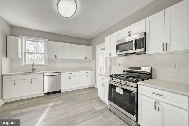a kitchen with granite countertop a sink stainless steel appliances and cabinets