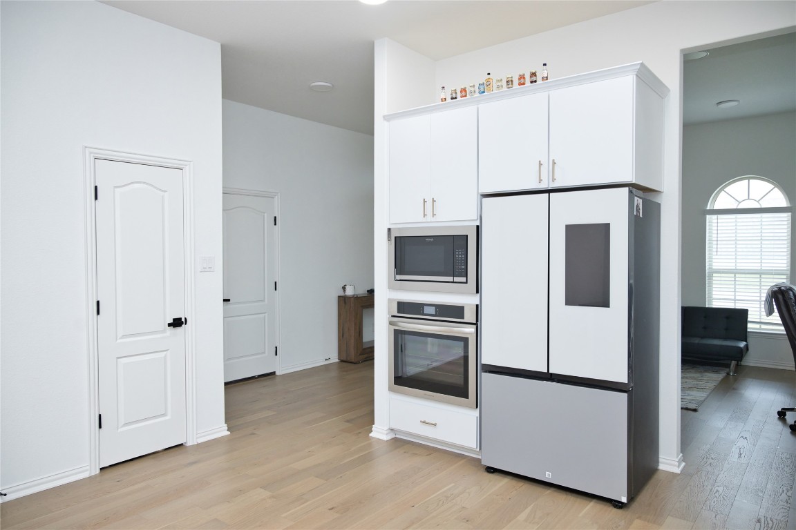 1209 Cole Ests Drive Georgetown, TX 78628 - Photo 9 of 33 Kitchen with appliances with stainless steel finishes, white cabinets, and light wood-style flooring