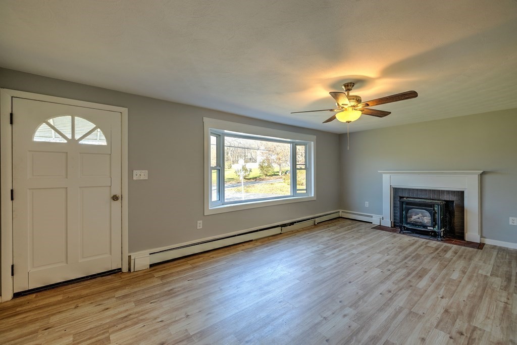 138 Coy Hill Road Warren, MA 01083 - Photo 4 of 42 an empty room with wooden floor a fireplace and windows