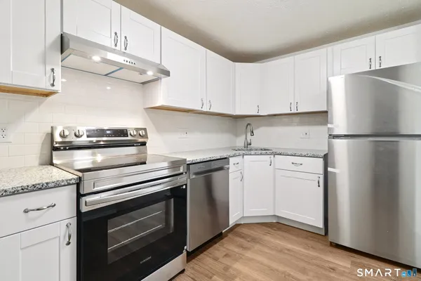 a kitchen with cabinets stainless steel appliances and wooden floor