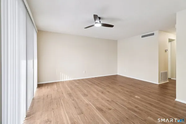 a view of an empty room with wooden floor and a window