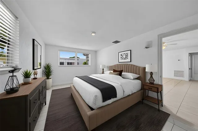 a bedroom with bed and a large mirror next to a window