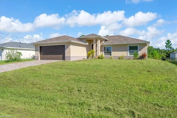a view of a yard in front of a house with a large tree