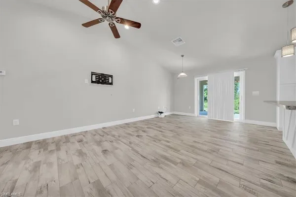 a view of an empty room and window with a ceiling fan