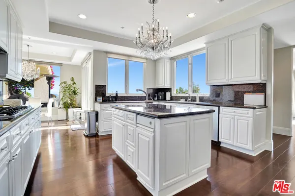 a kitchen with kitchen island granite countertop a stove top oven a sink and dishwasher with wooden floor