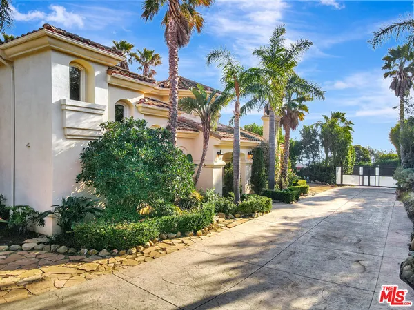 a front view of a house with a yard and potted plants