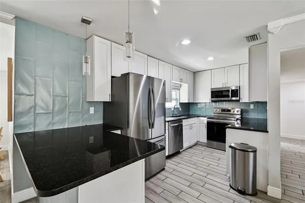 a kitchen with stainless steel appliances granite countertop a refrigerator a stove a sink and a microwave