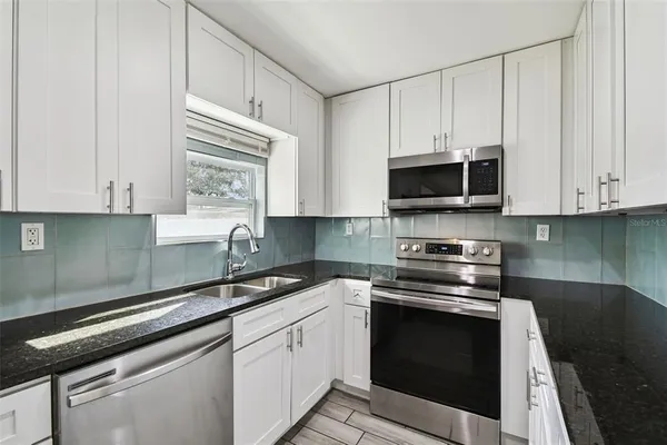 a kitchen with stainless steel appliances granite countertop white cabinets granite counter tops and a window