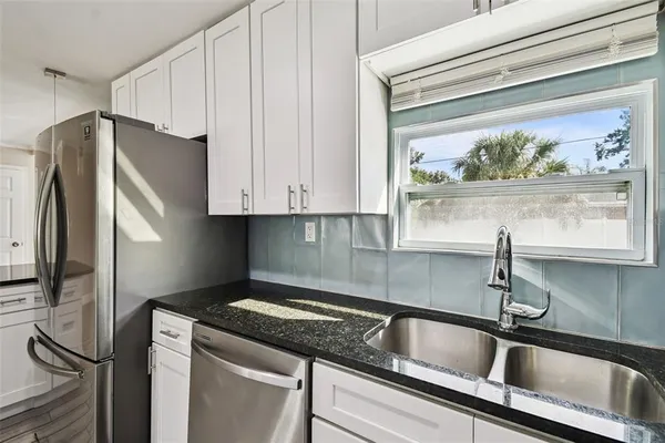 a kitchen with stainless steel appliances granite countertop a sink and a refrigerator