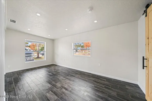 a view of an empty room with wooden floor and a window