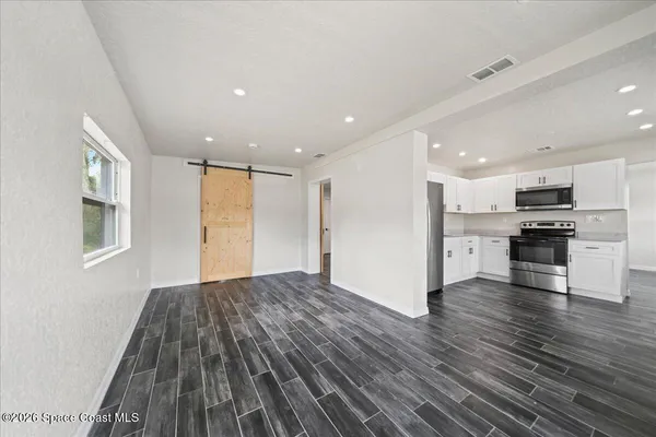 a view of kitchen with cabinets wooden floor and stainless steel appliances