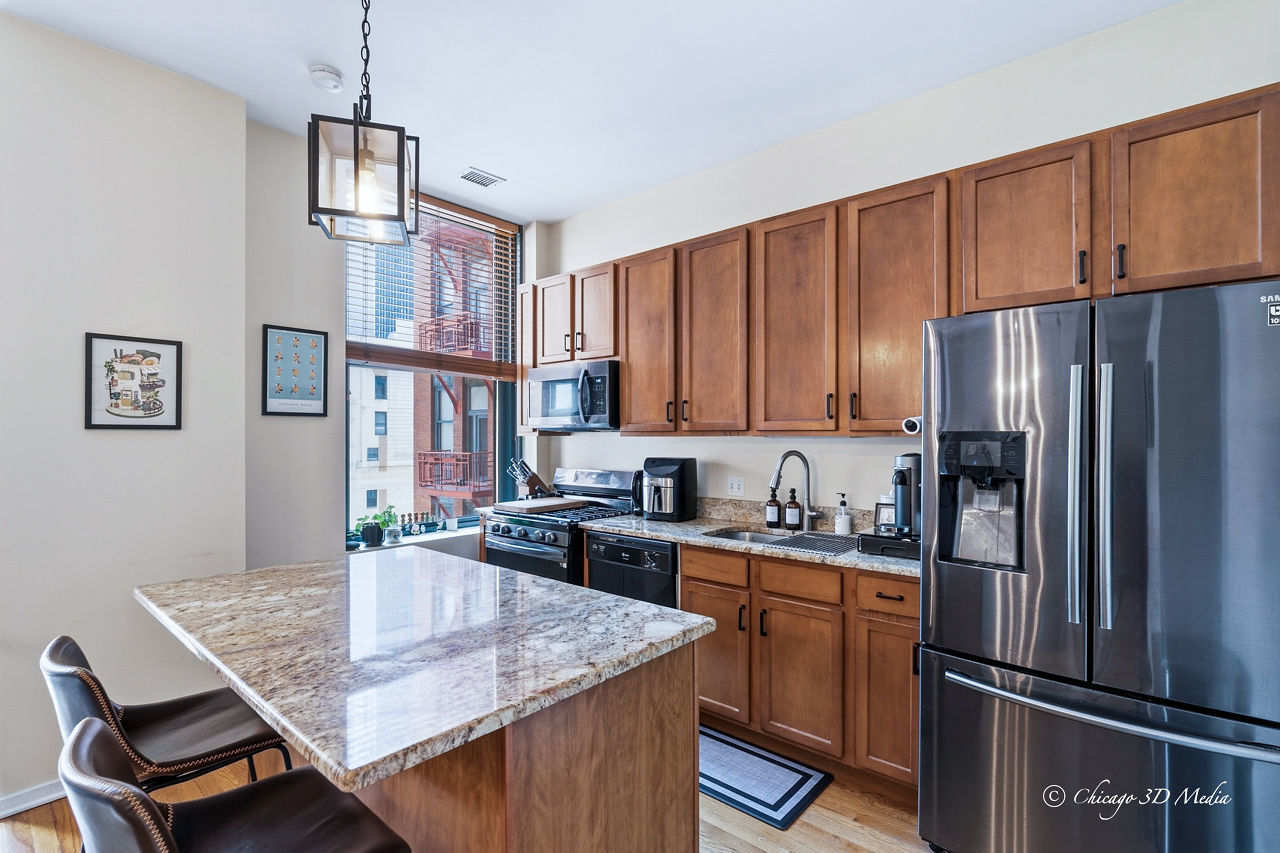 208 West Washington Street, Unit 1007 Chicago, IL 60606 - Photo 13 of 18 a kitchen with granite countertop a refrigerator a stove a sink dishwasher a dining table and chairs with wooden floor
