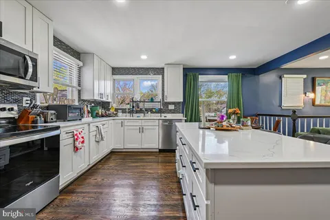 a kitchen with stainless steel appliances white cabinets a sink a stove a refrigerator and a window