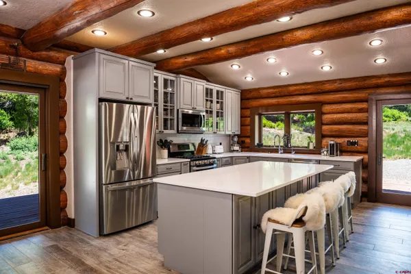 a kitchen with stainless steel appliances granite countertop a refrigerator a sink dishwasher a stove and a refrigerator with wooden floor