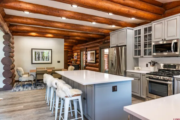 a kitchen with stainless steel appliances kitchen island granite countertop a table chairs and a refrigerator