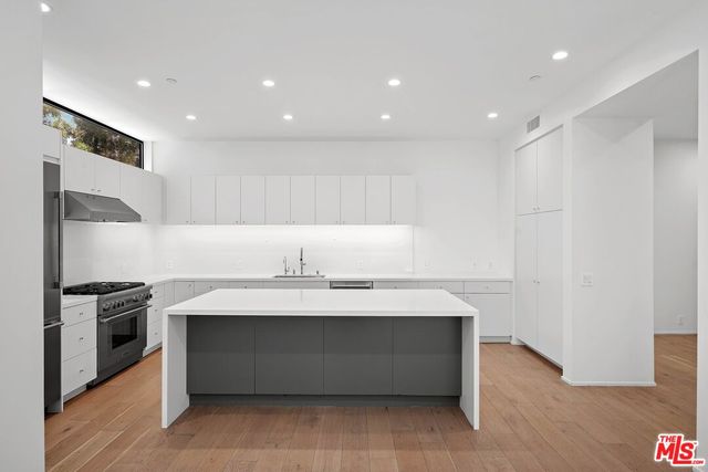 a view of counter top space with stainless steel appliances wooden floor and window