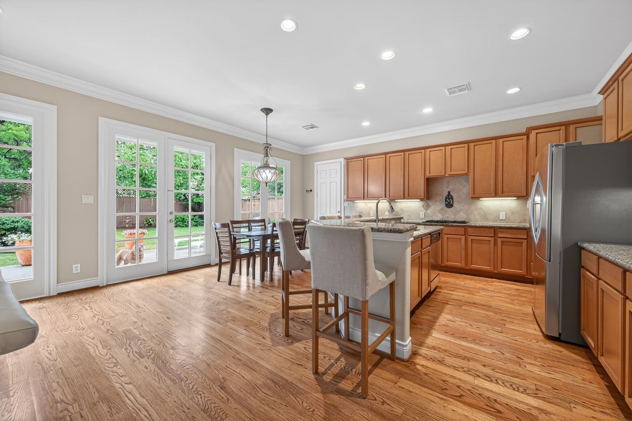 10932 Lasso Lane Houston, TX 77079 - Photo 9 of 38 a kitchen with stainless steel appliances granite countertop a stove top oven a sink dishwasher a dining table and chairs with wooden floor