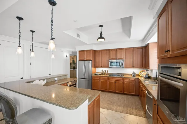 a large kitchen with kitchen island a large counter top space a sink a stove and a chandelier
