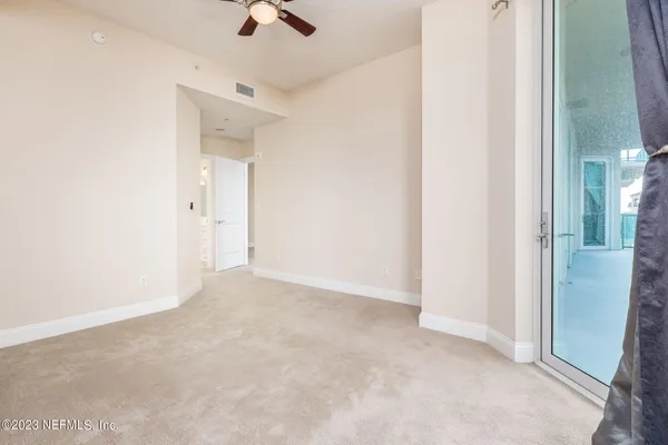 an empty room with a ceiling fan and carpet