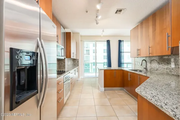 a large kitchen with granite countertop a large window and stainless steel appliances