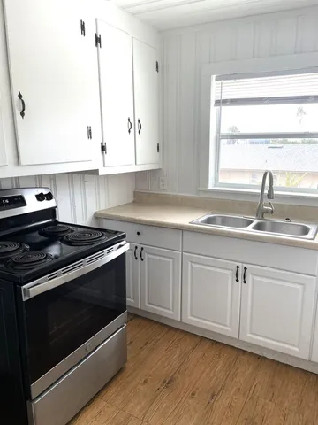 a kitchen with granite countertop white cabinets appliances and a sink
