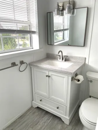 a bathroom with a granite countertop toilet sink and mirror