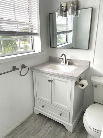 a bathroom with a granite countertop toilet sink and mirror