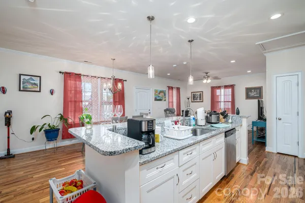 a kitchen with stainless steel appliances granite countertop a sink refrigerator stove and white cabinets with wooden floor