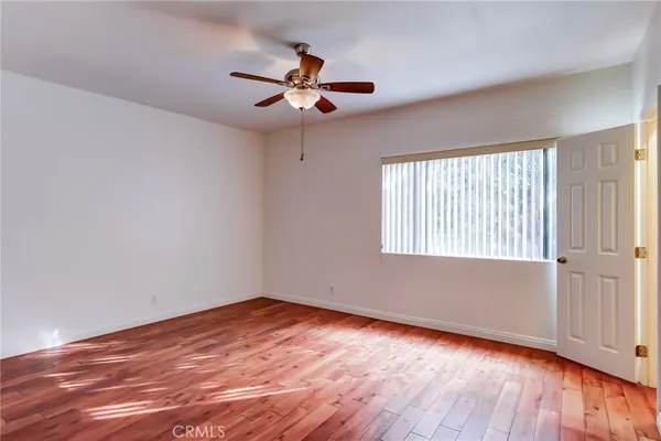 a view of empty room with wooden floor and fan