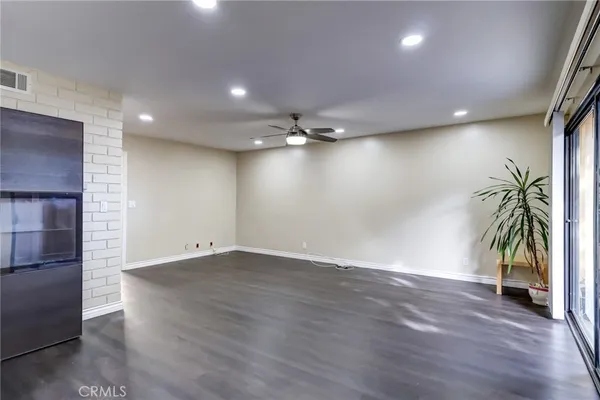 an empty room with wooden floor and a ceiling fan