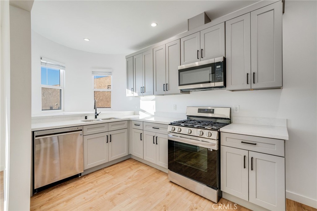a kitchen with stainless steel appliances granite countertop grey cabinets a sink and a stove