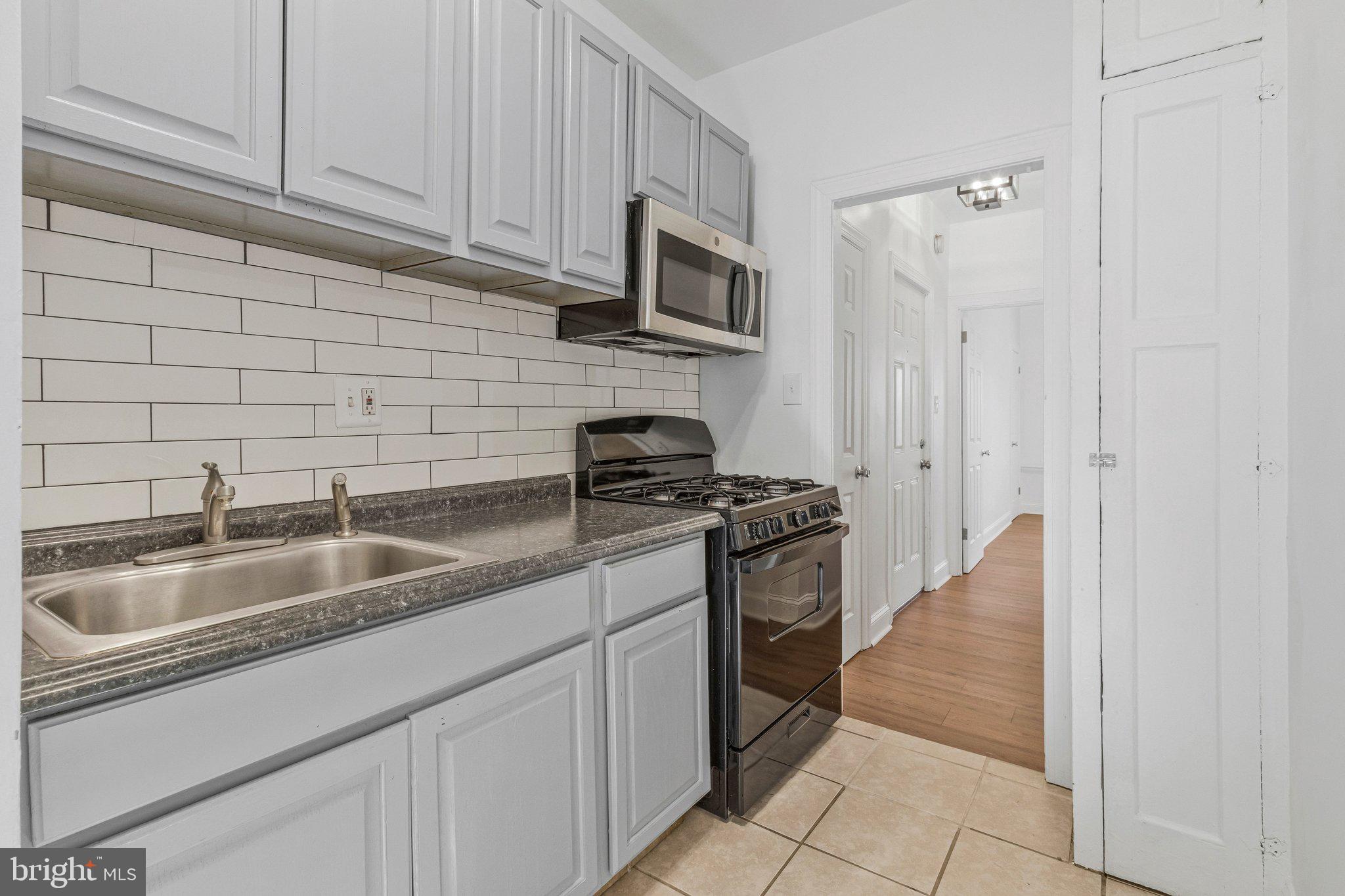 1111 Queen Street Northeast, Unit 3 Washington, DC 20002 - Photo 6 of 8 a kitchen with stainless steel appliances granite countertop a sink stove and refrigerator