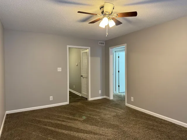 an empty room with closet and a chandelier fan