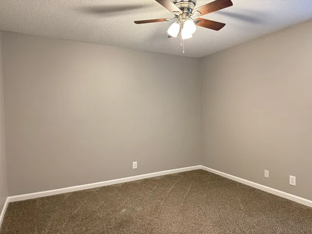 an empty room with a window and a fan