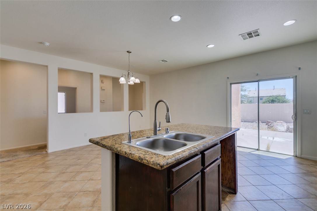5150 Riverside Run Court North Las Vegas, NV 89081 - Photo 34 of 50 A well-appointed kitchen island with dual sinks anchors this bright space, connecting seamlessly to an outdoor patio through sliding glass doors.