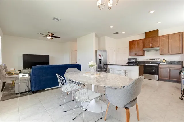 a living room with table chairs and refrigerator